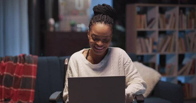 Cheerful satisfied afro-american disabled girl in wheelchair using laptop receiving job application emal rejoicing with clenchen fists celebrating.