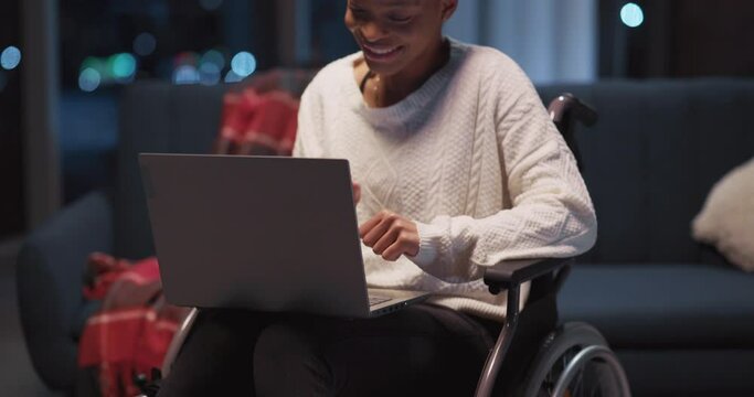 One beautiful afro-american disabled young woman sitting in wheelchair using portable laptop for freelance work project. Home interior.