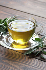 Sage herbal tea in a glass cup with fresh leaves on rustic wooden background, closeup, copy space,  natural medicine and healthy homeopathic herbs concept