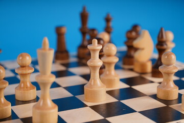 Close-up of chess on a blue background. Wooden chess pieces. Concept: the Board game and the intellectual activities