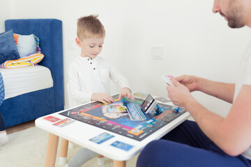 The man's father, playing a board game with her young son spend time together