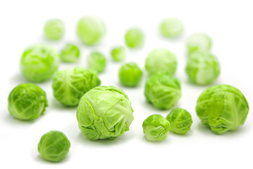 Fresh whole organic brussels sprouts scattered, isolated on white background.