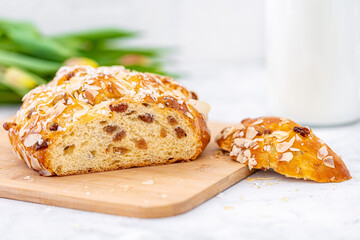 Osterbrot im Anschnitt mit Milch auf Holzbrett