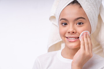 Close up portrait of a little teenage girl in bath towel using cotton pad isolated over white background © InsideCreativeHouse