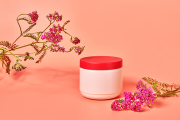 pink jar without inscriptions. against the background of red flower yarrow. concept cosmetics skin care © Olek