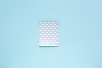 Health care concept. Blister pack with white pills on a blue background. Minimalism.