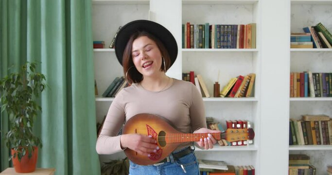 Woman musician blogger at home playing national guitar. Blogger influencer, recording vlog stream  concert and music tutorial on mobile phone. Online broadcasting.