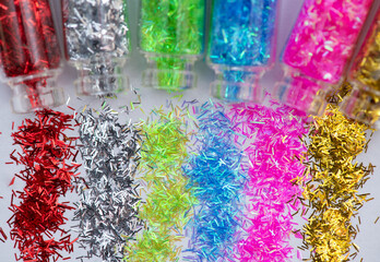 Assortment of glitter nail and make-up multi-colored in glass bottles on white background. Macro	