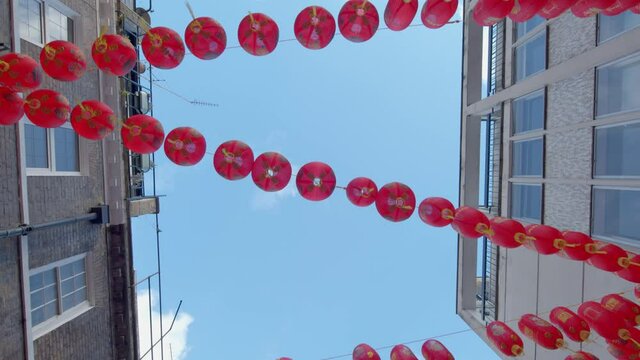 Tracking shot Looking up at red Chinese lanterns dangling in Chinatown in London during Chinese New Year