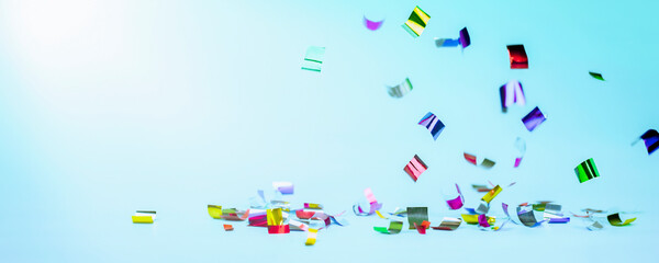 Fototapeta na wymiar falling multicolored confetti on a light blue background. holiday background