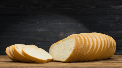 Sliced bread. Bread slices on natural wooden background. Industrial baking bread made from white flour. Copy space.