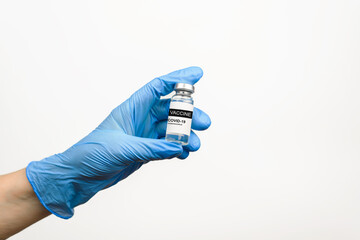 Coronavirus vaccine covid-19, vaccination concept. Hand in medical glove holding vial of medicine on white background, close-up