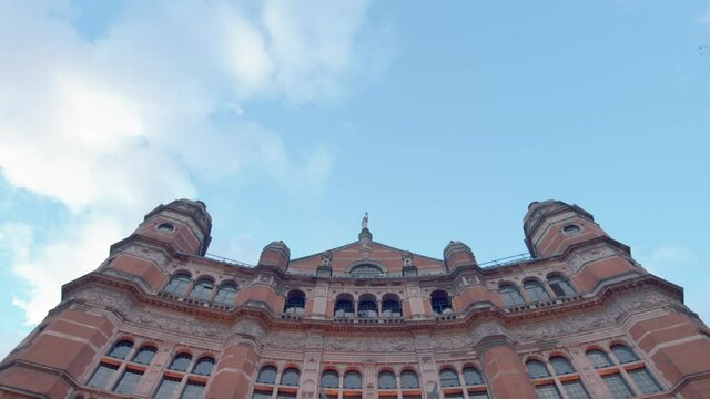 Low angle shot looking up at Palace Theatre London with blue sky and white clouds and birds flying across