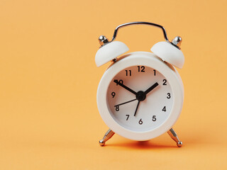 White alarm clock on a yellow background.