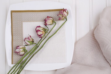 Róże suche na białym kwadratowym talerzu z serwetką © Seance_Photo_Sylwia