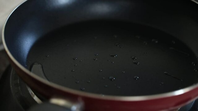 Frying pan with hot sunflower oil getting spread on whole surface