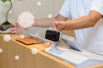 白衣を着た男性が受付に飛沫防止用のアクリル板を設置するシーン　感染症対策　新しい生活様式	