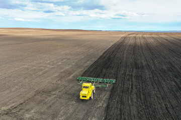 Seasonal agricultural work. A lone tractor is harrowing the arable land. Shooting from a drone.