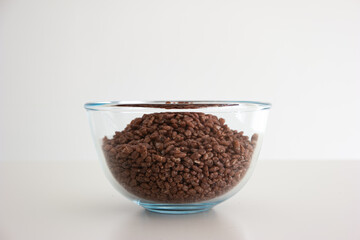 Glass bowl of chocolate breakfast cereal isolated on white background
