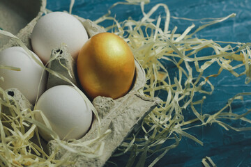 Box with gold and white eggs on color background