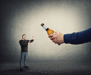 Stop consuming alcohol concept. Man refuse to take a bottle of beer from an giant hand, as metaphor for win against addiction. Guy reject drinking alcohol. Facing bad habits, healthy lifestyle - obrazy, fototapety, plakaty