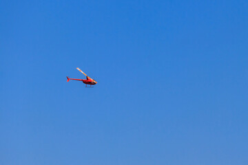 Flying orange helicopter in blue sky
