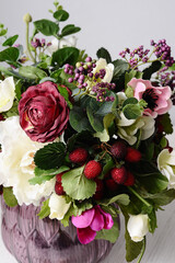 Elegant flower composition in purple vase. Tender bouquet ofred and ivory flowers on grey background. Interior decoration. Valentines day present.