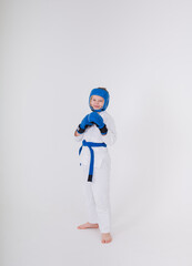 boy in a white kimono, sports helmet, boxing gloves stands in a pose on a white background with a place for text