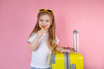 Little traveler with a yellow suitcase on a pink background