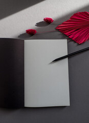 Blank, black notebook page isolated on grey background with pink flowers