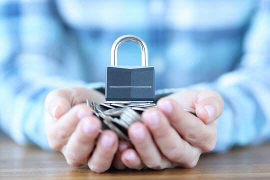 Female hand holding bunch of coins and padlock closeup