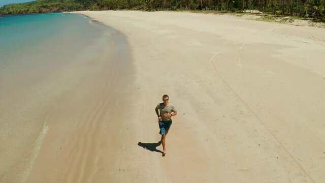 man jogging on tropical sandy beach near sea. Man running on tropical beach. Nacpan, El Nido, Palawan, Philippines