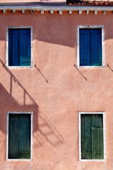 Pink Venice House with blue and green shutters, italy architecture.