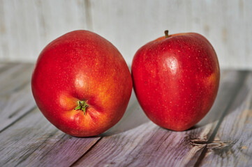 Apples lit from the sun decoratively lying on a wooden underground.