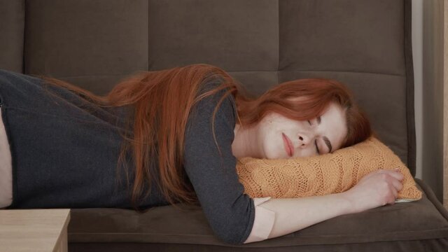 Sleepy red hair female student falls down on sofa. Exhausted, bored, apathetic girl.