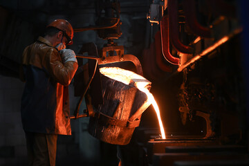 A steelmaker pours pig iron from a blast furnace, sparks and splashes of hot metal fly. - obrazy, fototapety, plakaty
