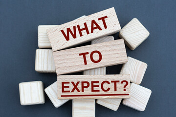 WHAT TO EXPECT? - words on wooden bars on cubes on a gray background