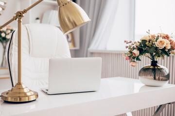 female office with a workspace desk in a light modern style with white furniture with laptop on...