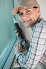 female builder installing window in a building