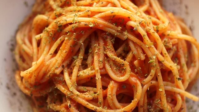 Pasta with tomato sauce. Italian spaghetti pasta with tomato sauce rotates on a white plate against a kitchen background. Italian Cuisine.