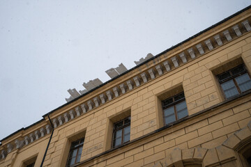Overhanging snow slabs on the roof of town house