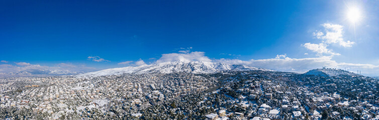 Attica Greece. Penteli mountain covered with snow, aerial drone view, blue sky background