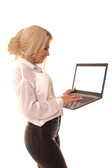 Blonde stands on a white background with a laptop in her hands. Girl typing on a laptop while standing in a white studio.