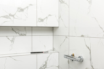 Shower interior. Shower faucet with thermostat. There is an adjustable wrench in the niche.
