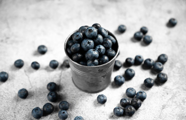 Fresh blueberries in a small metal bucket surrounded with some berries against concrete background. Top view. Rustic.