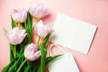 Banner. A bunch of pink tulips on a warm pink background with a card with HAPPY BIRTHDAY text and a gift bag. Flatlay