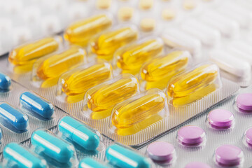 A bunch of medical pills in yellow and other colors. Tablets in plastic packaging.