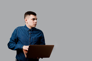 Handsome man with laptop on the gray background. Business man working online at home.