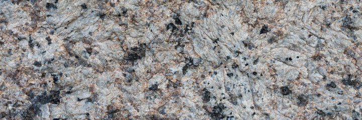 Granite texture. Natural gray granite with a grainy pattern. Stone background. Solid rough surface of rock. Durable construction and decoration material. Close-up.