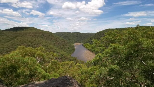 Beautiful video of a mountain top lookout of a creek with mountains and valleys on all sides and deep blue sky with puffy clouds, Naa Badu Lookout, Berowra Heights, Berowra Valley National park, Sydne